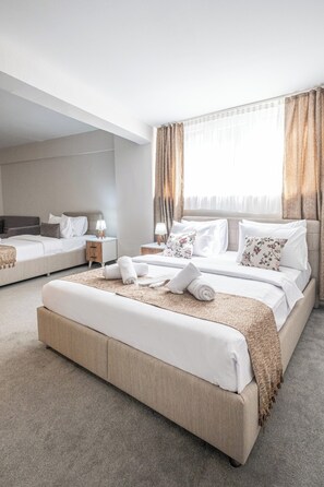 A modern hotel room with a large bed, two bedside tables, and a view of the city. - Oban Suites İstanbul (Istanbul)
