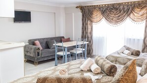 A hotel room with a large bed, a sofa, a dining table, and curtains. - Oban Suites İstanbul (Istanbul)