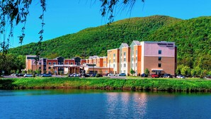 A hotel with multiple buildings, a parking lot, and a body of water in the foreground. - SpringHill Suites by Marriott Fishkill (Fishkill)