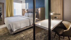 A modern hotel room with a large bed, a desk, and a chair. There is a window with curtains, a wall-mounted lamp, and a mirror. - SpringHill Suites by Marriott Fishkill (Fishkill)