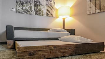 A bed with a wooden frame, white bedding, and a wall-mounted lamp.