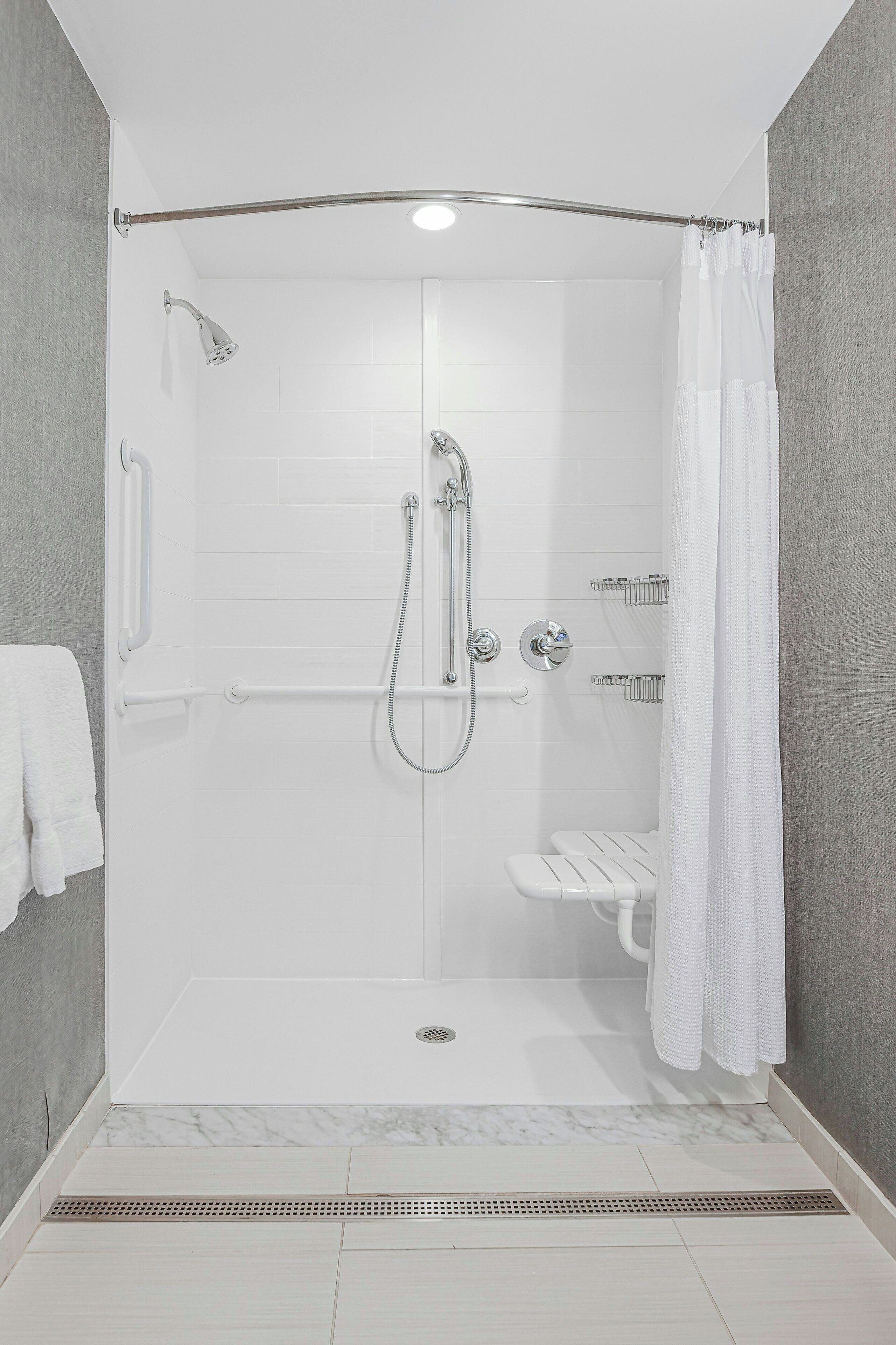 A walk-in shower with a glass door, a handheld showerhead, a handheld showerhead, a towel rack, and a toilet.