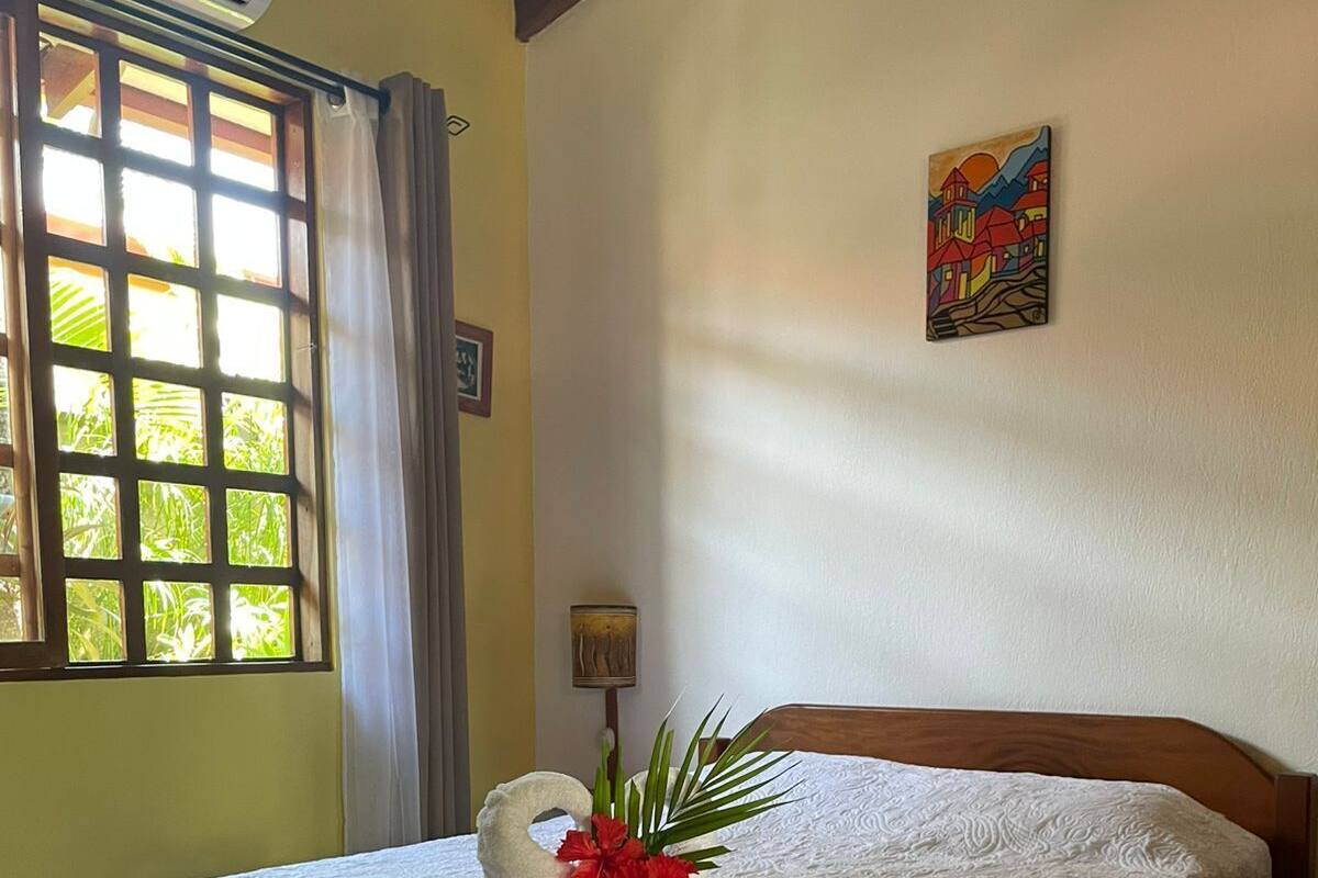 A neatly made bed with a white bedspread and a decorative swan-shaped towel arrangement.