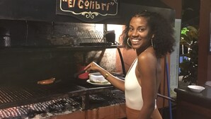 A person cooking on a grill with a sign above reading "El Colibri". - Cabinas el Colibri (Puerto Carrillo)