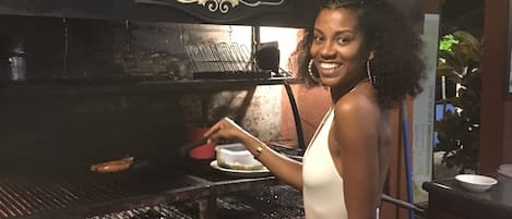 Une personne cuisine sur un barbecue, et une pancarte au-dessus indique « El Colibri ».