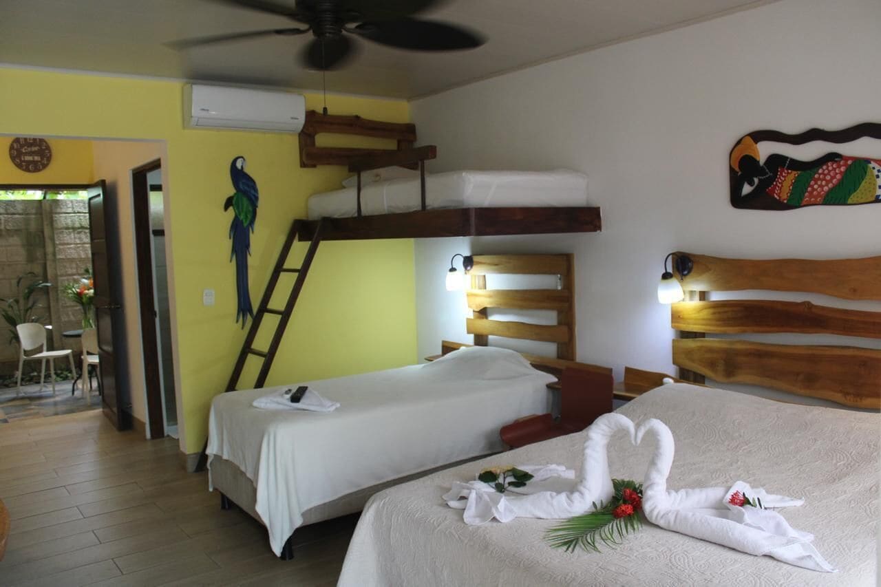 Habitación de hotel con dos camas, cabecero de madera, ventilador de techo y un adorno en la pared.
