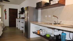 A modern kitchen with a stainless steel refrigerator, a built-in oven, and a marble countertop. - Cabinas el Colibri (Puerto Carrillo)