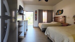 A hotel room with a kitchenette, two beds, a ceiling fan, and a view of the outdoors. - Cabinas el Colibri (Puerto Carrillo)