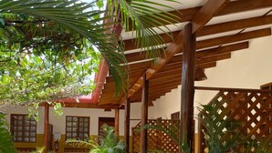 A covered outdoor area with a wooden pergola, potted plants, and a seating area with benches. - Cabinas el Colibri (Puerto Carrillo)