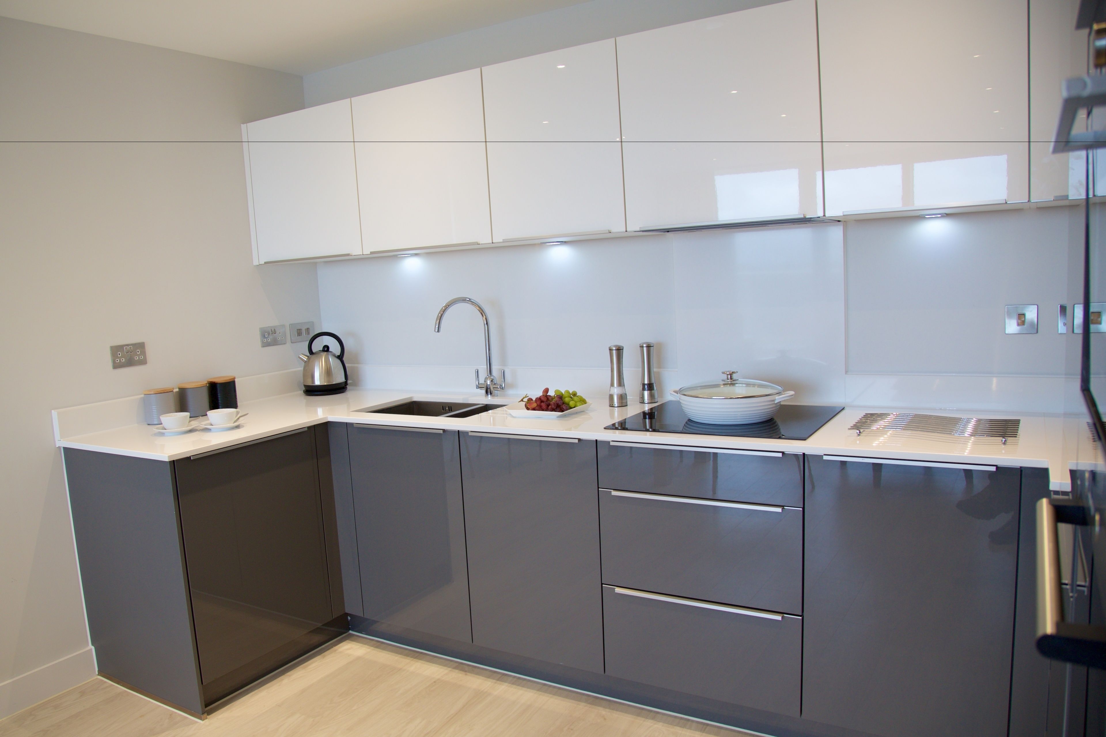 A modern kitchen with grey cabinets, a stainless steel sink, and a built-in oven.