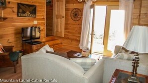 A cabin interior with wooden walls, a ceiling fan, a television, and a sofa.