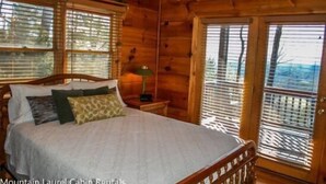 A wooden cabin bedroom with a bed, nightstands, and a window with blinds.
