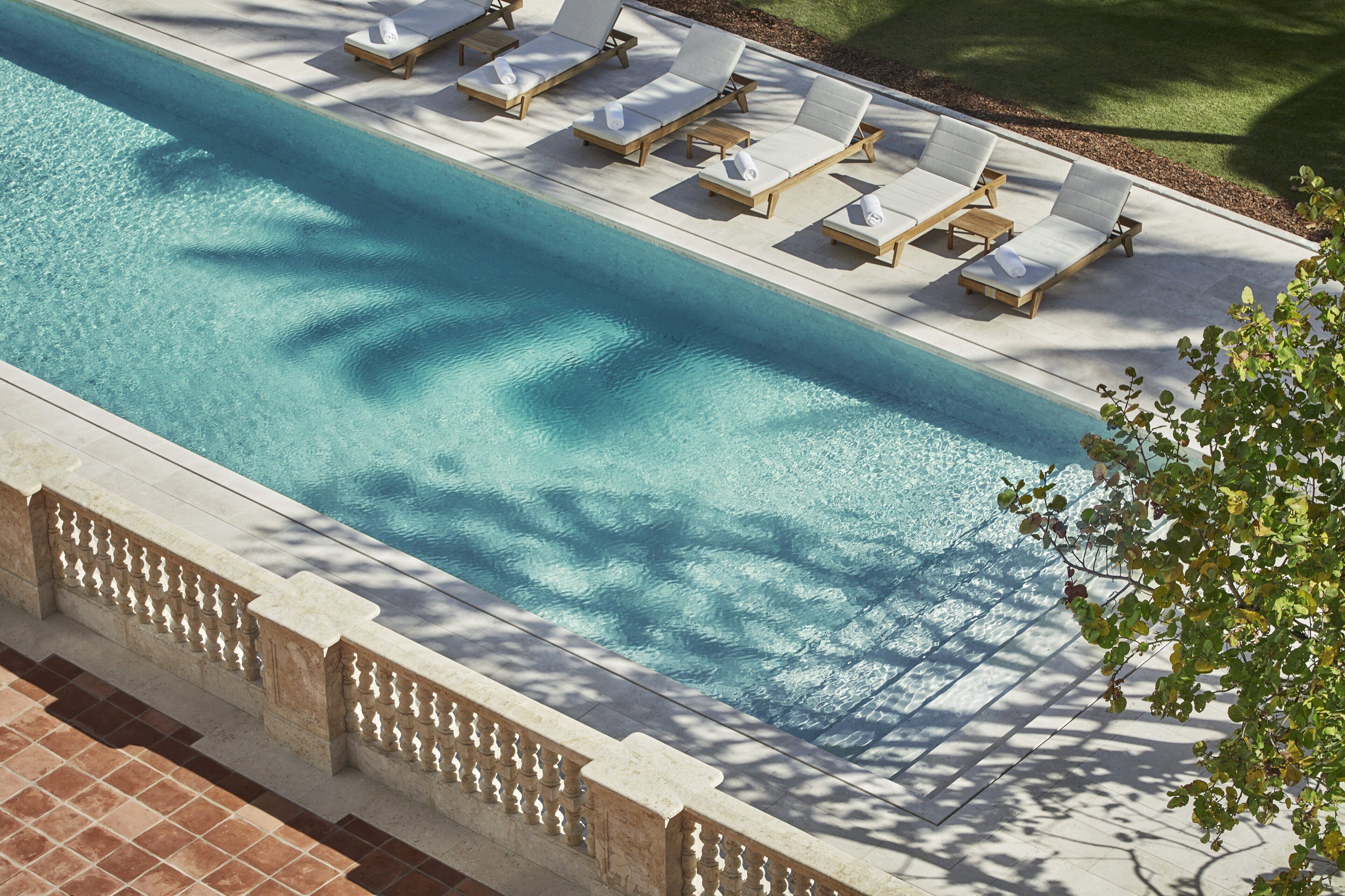 Piscina com espreguiçadeiras e um deck revestido de azulejos.