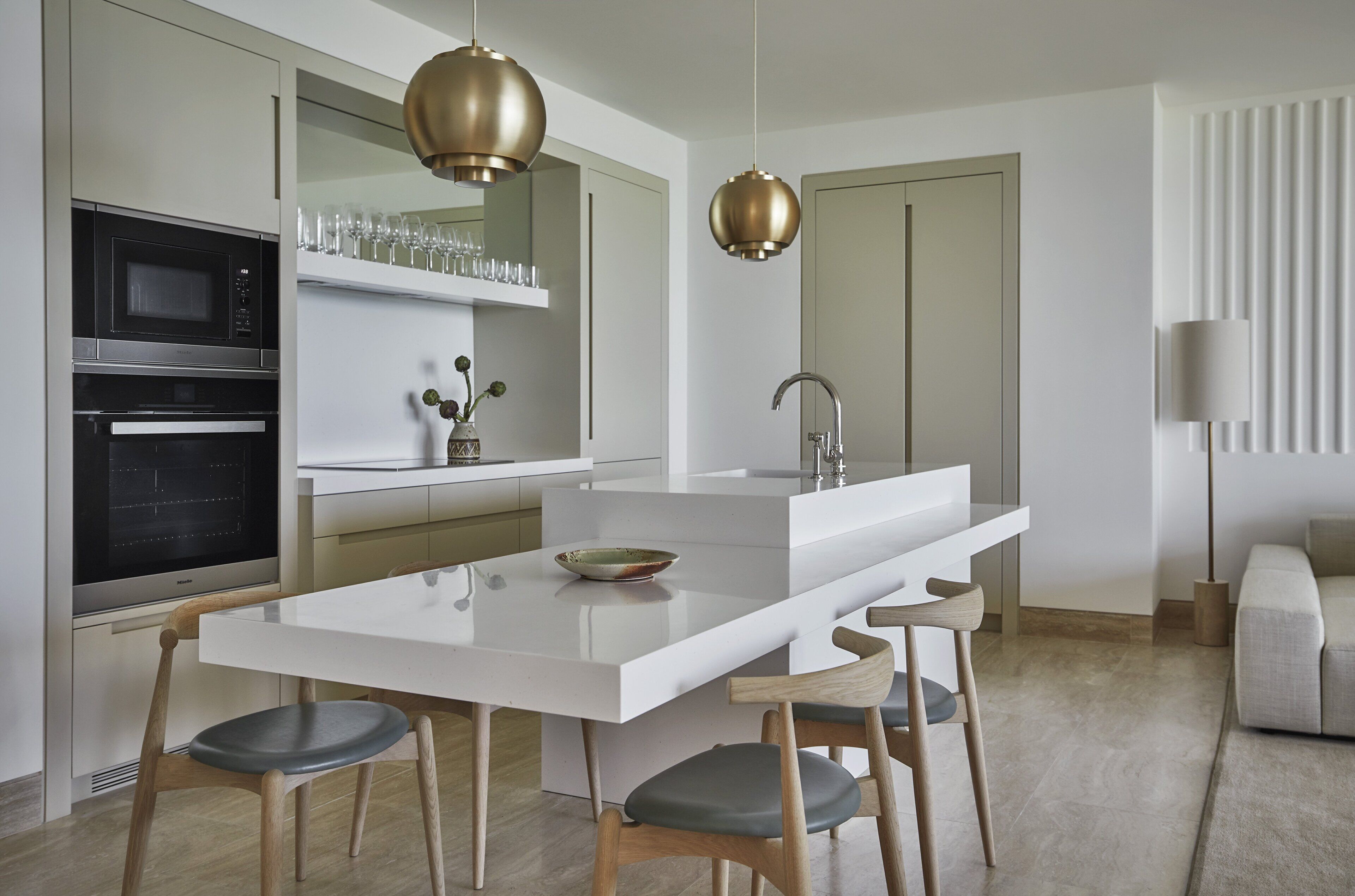 A modern kitchen with white cabinetry, stainless steel appliances, and a central island with seating.