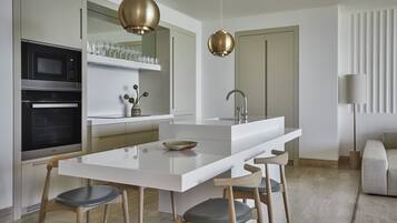 A modern kitchen with white cabinetry, stainless steel appliances, and a central island with seating.