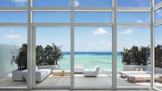A modern interior with large windows offering a view of the ocean. - Four Seasons Hotel at The Surf Club (Surfside)