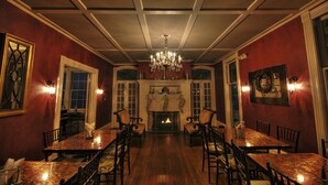 A formal dining room with a long table, chairs, a chandelier, and a fireplace. - Vandiver Inn (Havre De Grace)