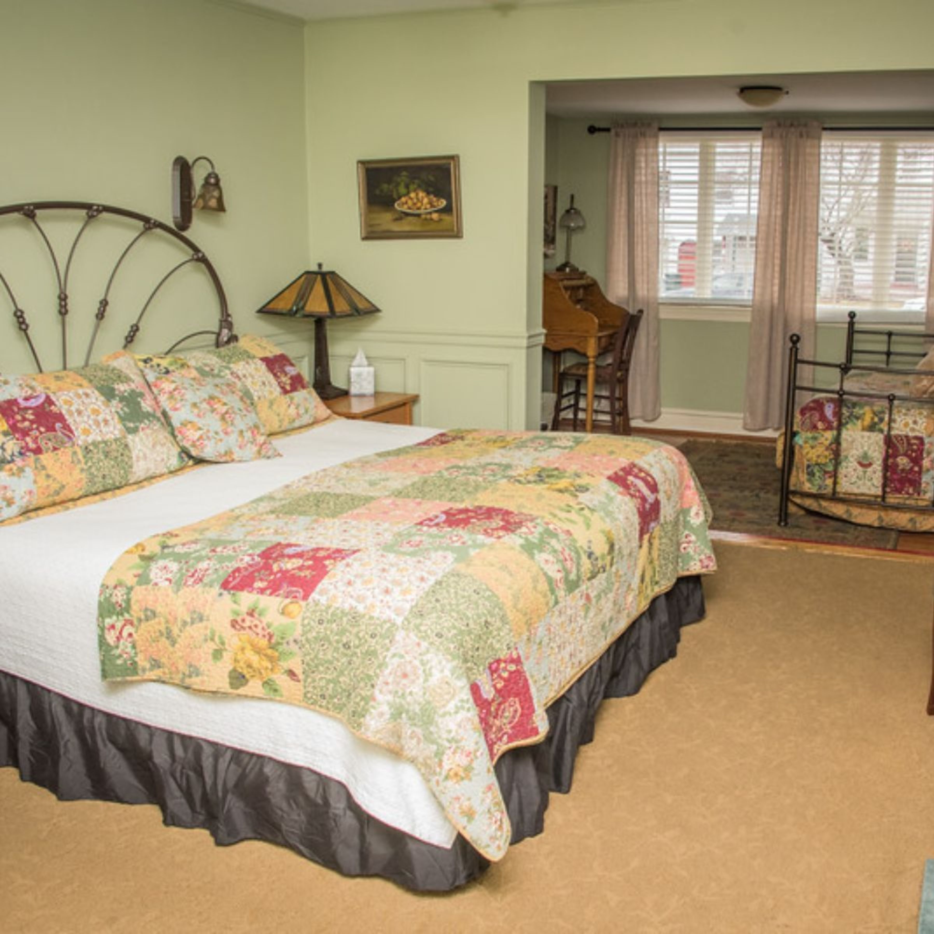 Un dormitorio con una cama grande, una mesita de noche, una lámpara, una silla y una ventana con cortinas.