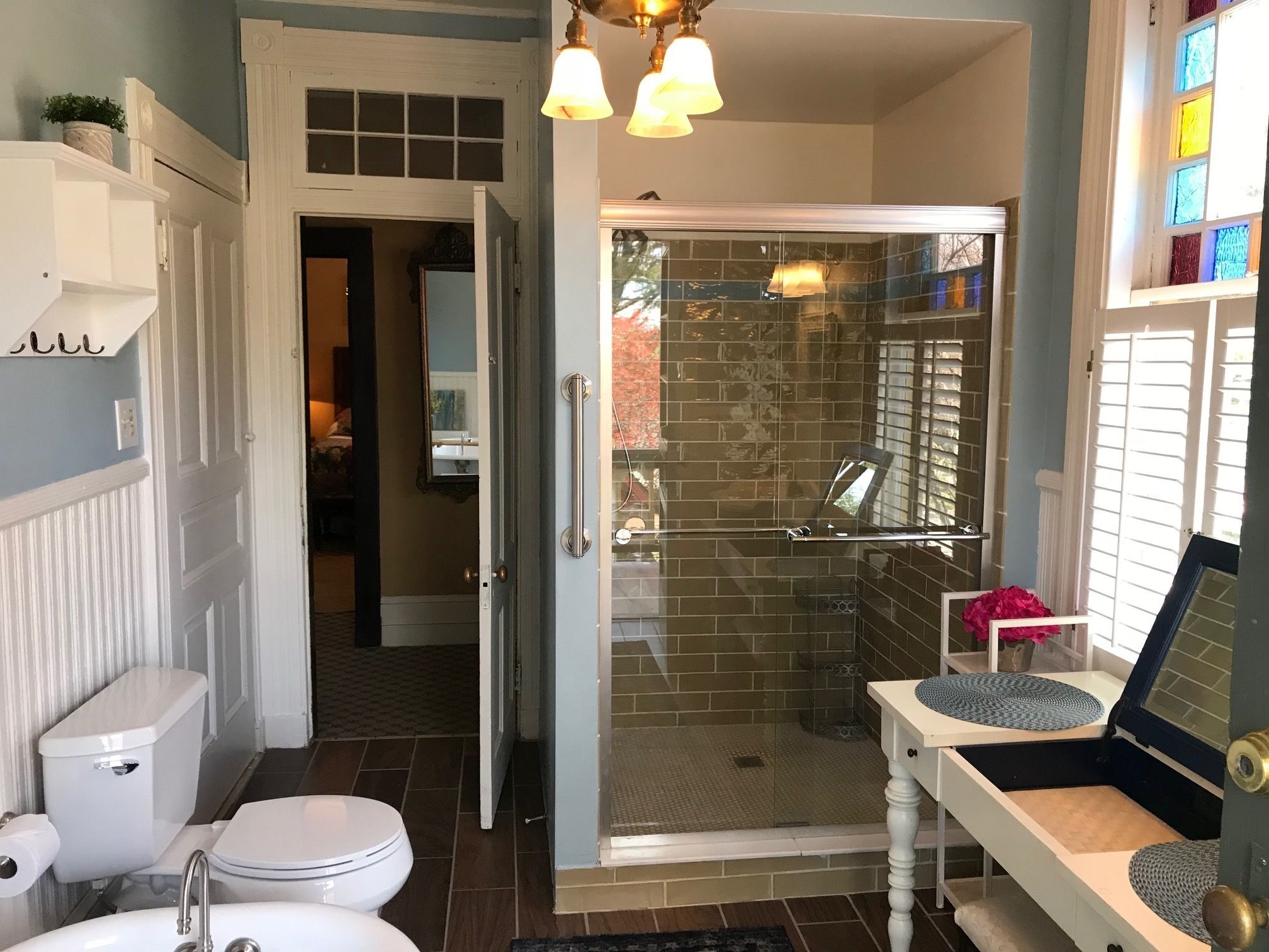 A bathroom with a glass-enclosed shower, a toilet, and a sink.