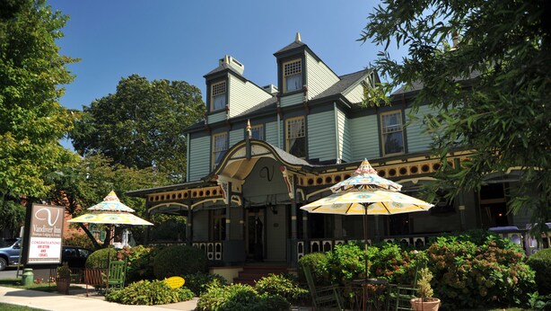 A Victorian-style building with a porch, outdoor seating, and a sign for Vandiver Inn. - Vandiver Inn (Havre De Grace)