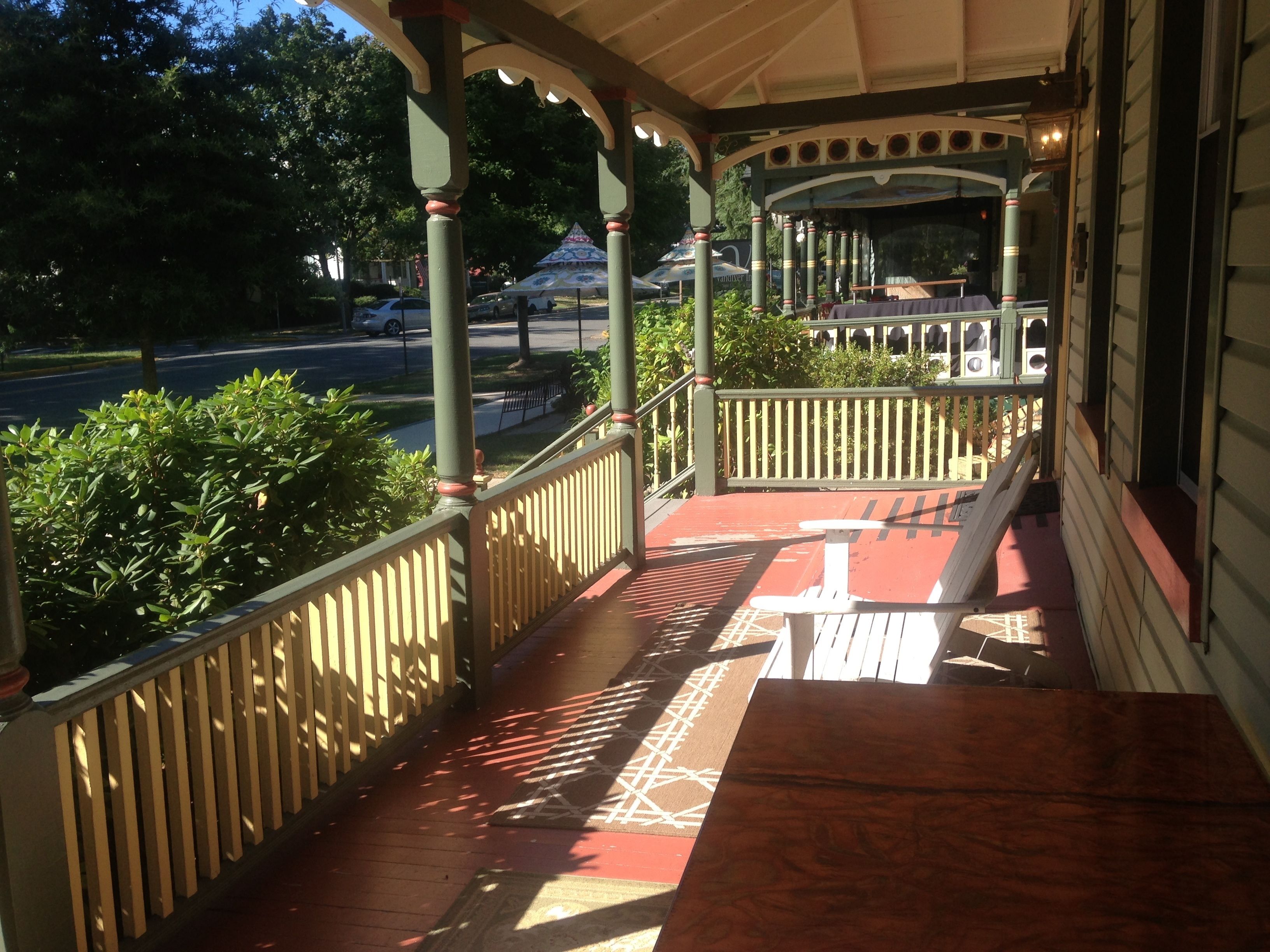 A covered porch with a wooden railing and a bench.