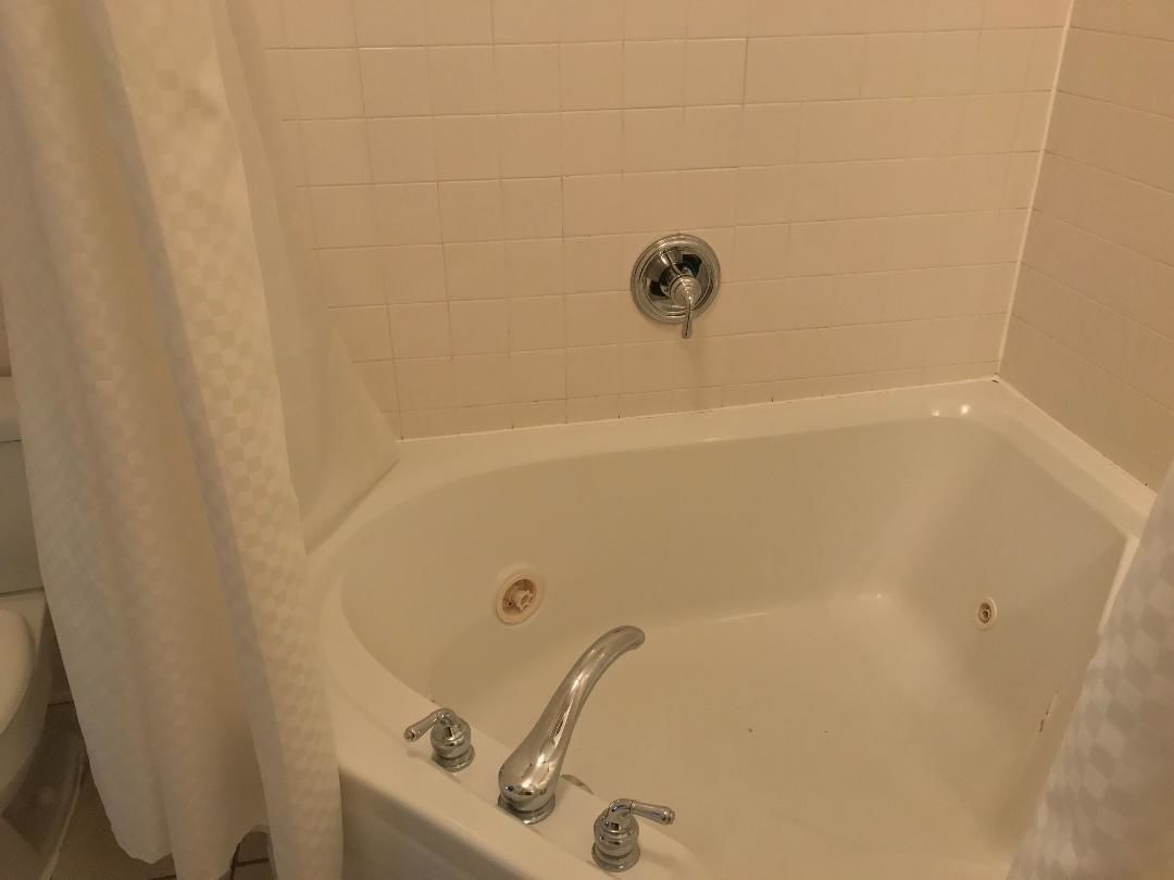 A bathroom with a white bathtub, a shower curtain, and a toilet.