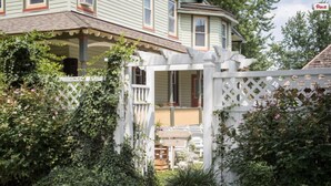 A traditional house with a covered porch, white picket fence, and lush greenery. - Vandiver Inn (Havre De Grace)