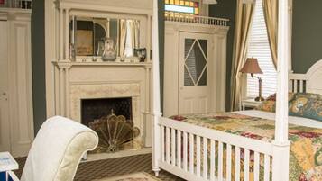 A traditional bedroom with a four-poster bed, a fireplace, and a chandelier.