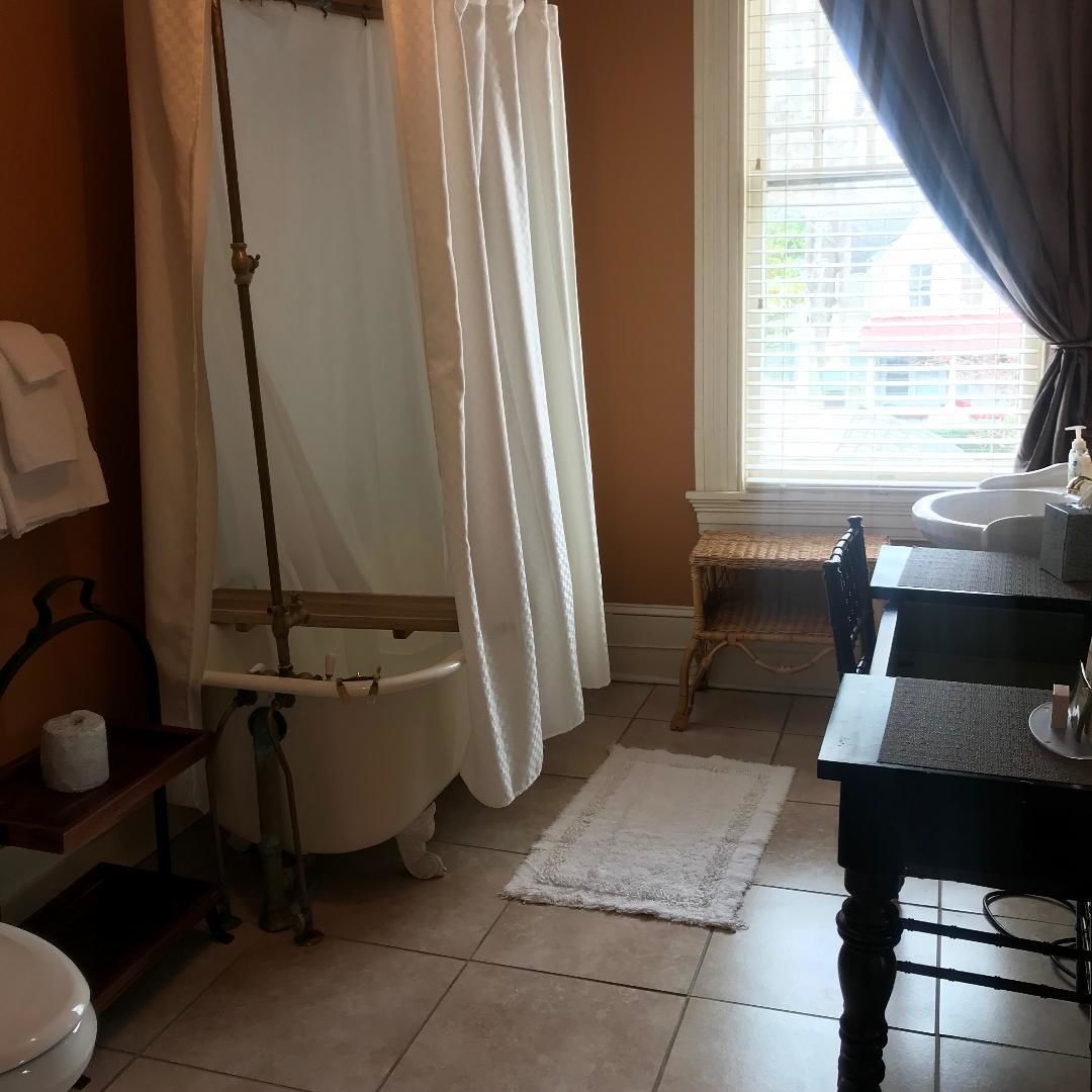 A bathroom with a bathtub, a toilet, a sink, and a window with curtains.