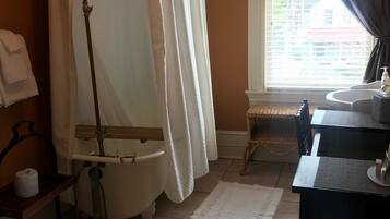 A bathroom with a bathtub, a toilet, a sink, and a window with curtains.