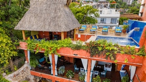 A hotel with a pool, outdoor seating, and lush greenery. - Villa Lola - an Adults Only Bed & Breakfast (Puerto Vallarta)