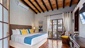 A bedroom with a large bed, a wooden ceiling, a tiled floor, a balcony with a chair, and a dresser. - Villa Lola - an Adults Only Bed & Breakfast (Puerto Vallarta)