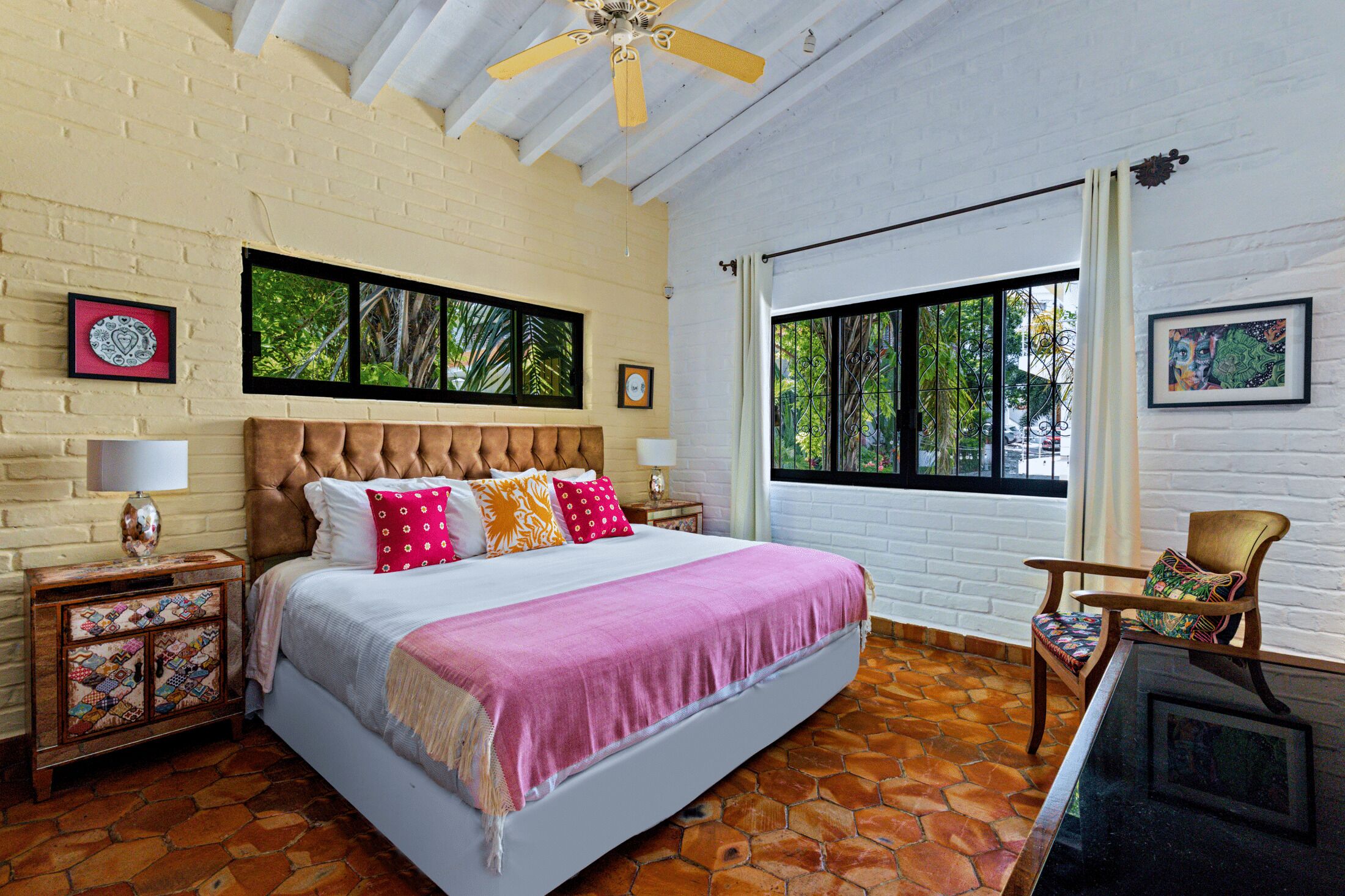 Un dormitorio con una cama grande, una mesita de noche de madera, una silla y una ventana con vistas a zonas verdes.
