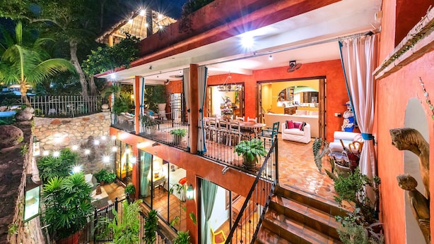 A multi-level outdoor patio with stone walls, potted plants, and a dining area. - Villa Lola - an Adults Only Bed & Breakfast (Puerto Vallarta)