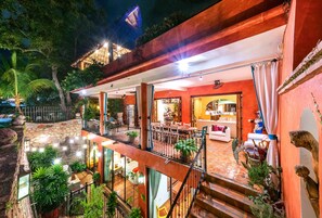 Un patio exterior de varios niveles con muros de piedra, plantas en macetas y una zona de comedor.