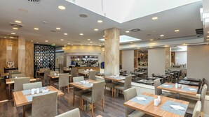 Un restaurant moderne doté de plusieurs espaces de restauration, d’un bar et d’une cuisine ouverte.