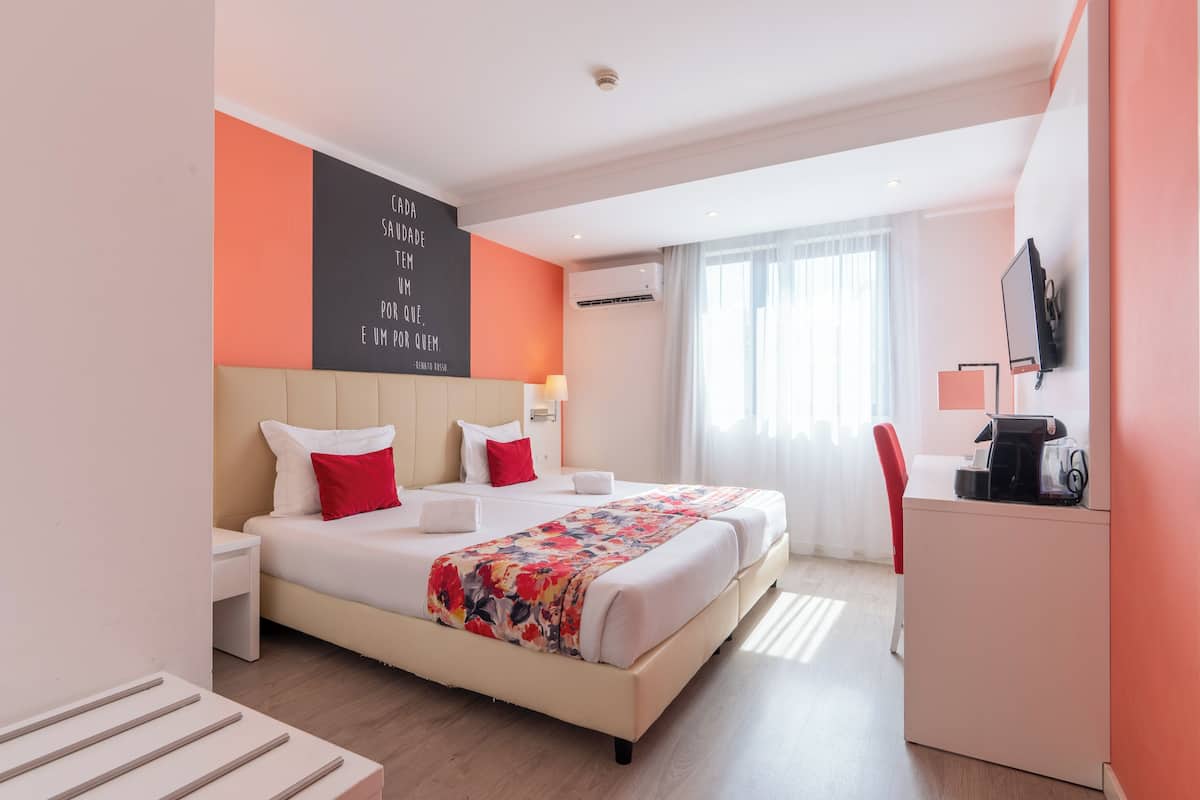 Een hotelkamer met een bed, bureau, televisie en een raam met gordijnen.