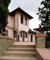 A pink building with a stone staircase leading to the entrance.