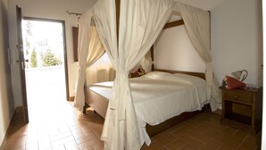 Une chambre à coucher avec un lit à baldaquin, une table de chevet en bois et une vue sur l’extérieur.