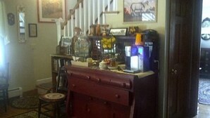 Une pièce comprenant un meuble en bois, une machine à café, une chaise et un tapis.