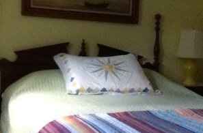 A bed with a white comforter and a colorful striped blanket.