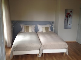 A double bed with a headboard, two pillows, and a wooden floor.
