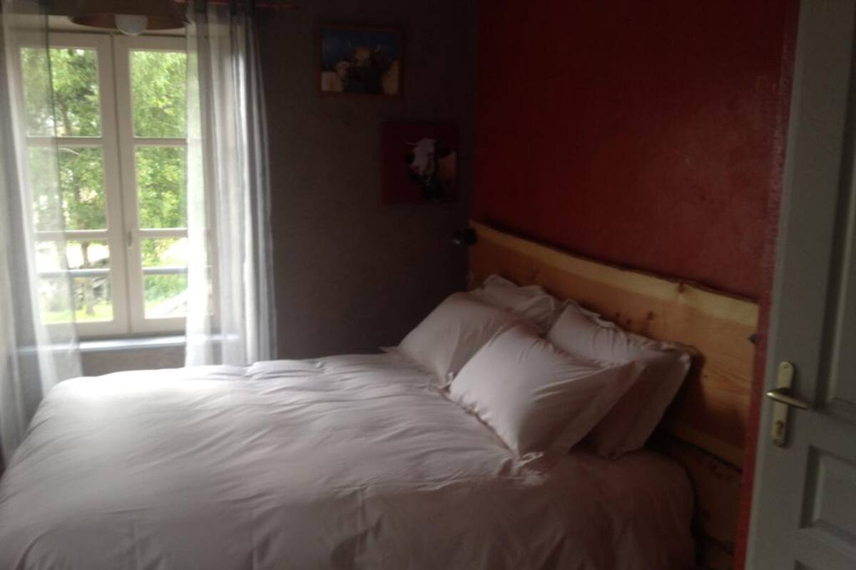 Un dormitorio con una cama grande, cabecera de madera y ventana con cortinas.