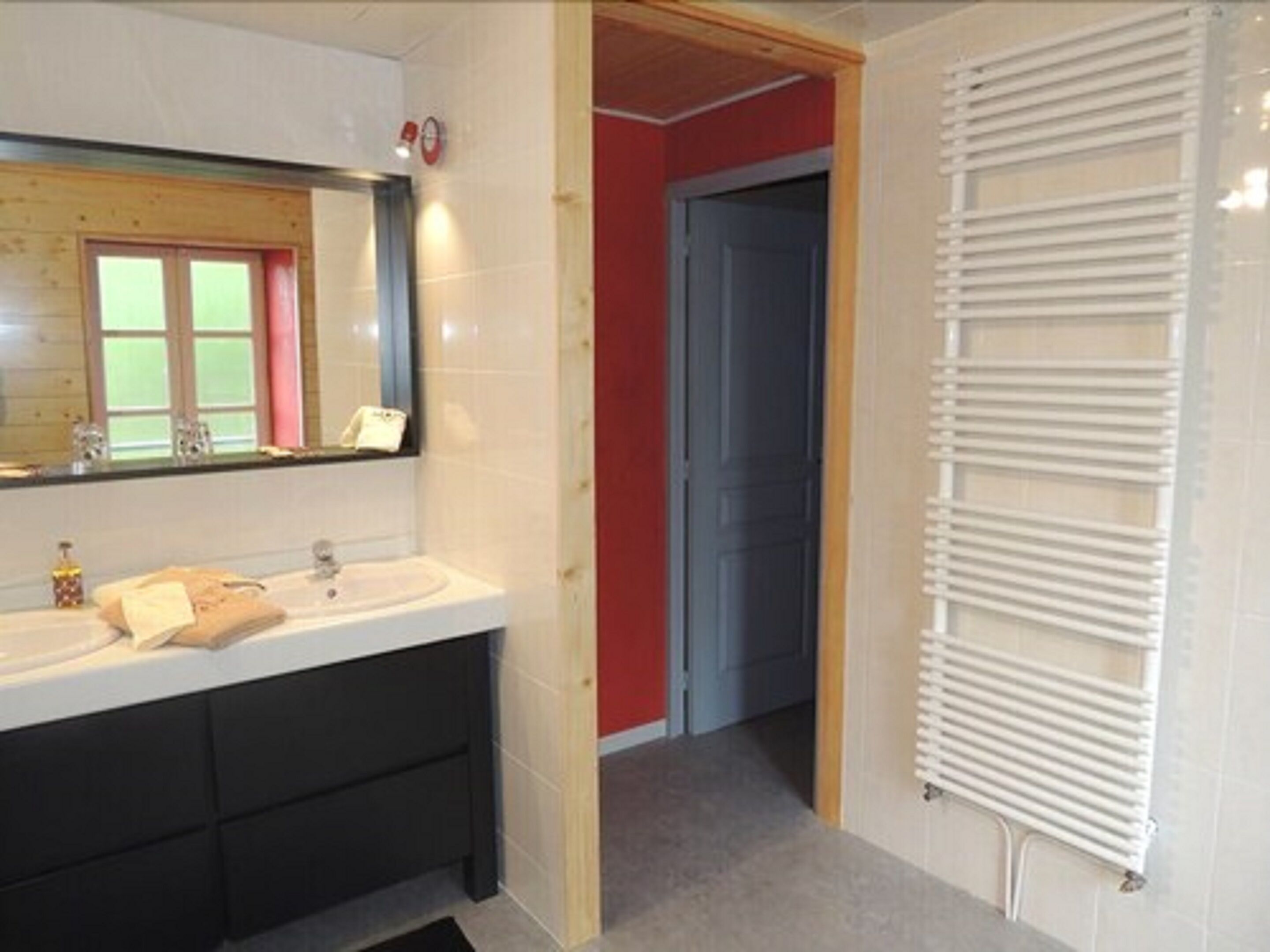 Un baño con lavamanos blanco, un espejo, una toalla y un radiador blanco.