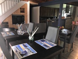 A dining area with a table set for four, featuring magazines and a glass vase with sticks.