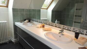 Un baño con dos lavamanos, un espejo grande y un tragaluz.