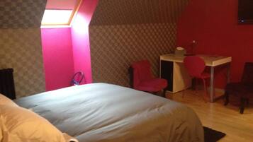 A bedroom with a bed, a desk, and two chairs.