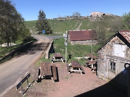 A rural roadside with picnic tables and a stone building.