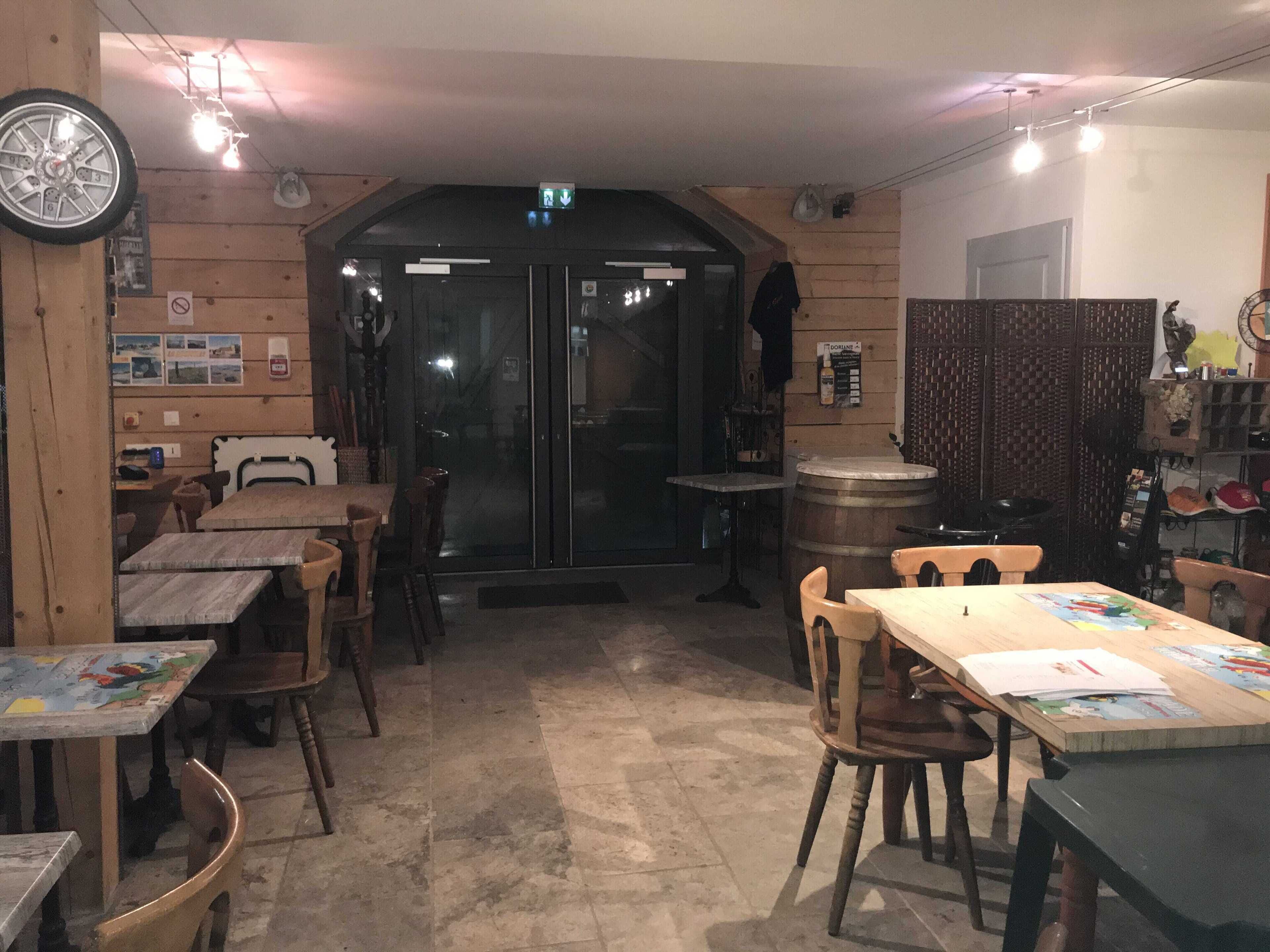 A cozy restaurant interior with wooden walls, a large wooden barrel, and several tables and chairs.