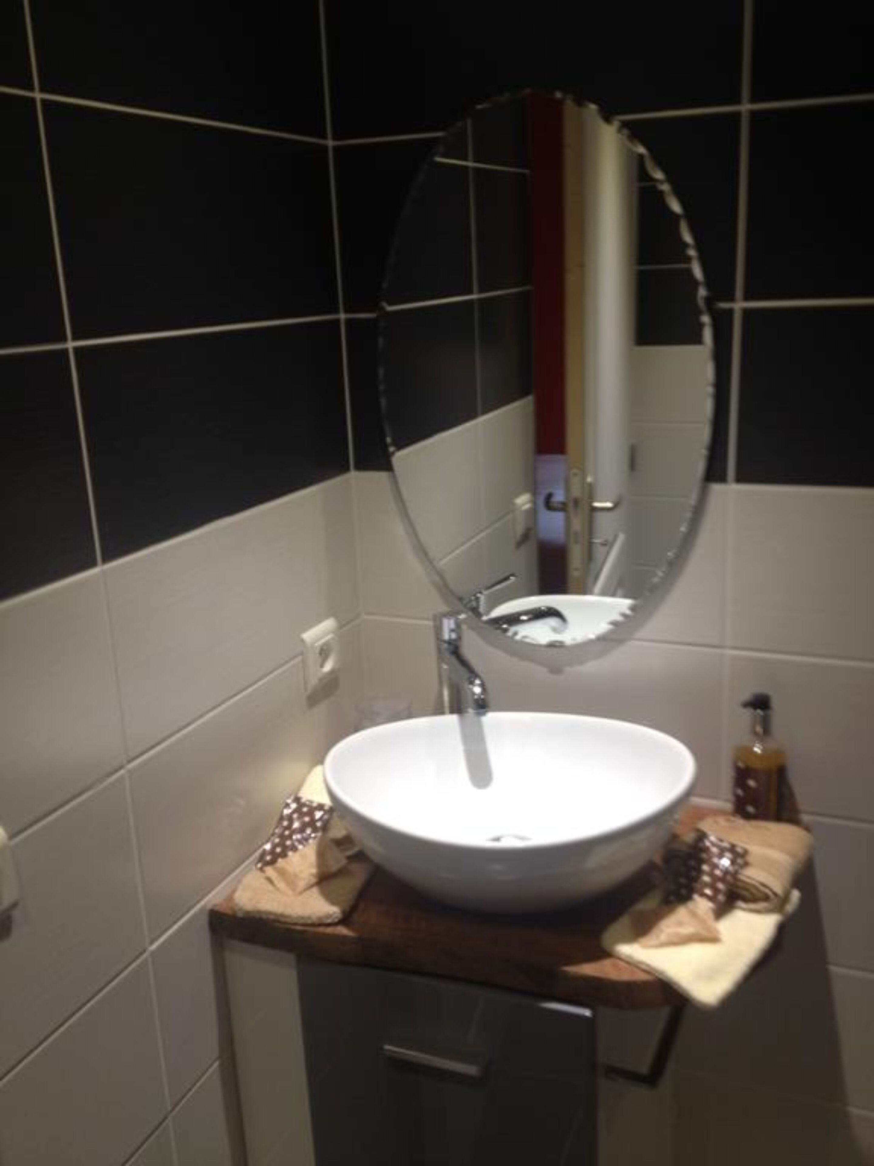 A bathroom with a white sink, a mirror, and a wooden countertop.